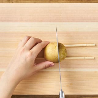 【画像】洗ったじゃがいもに皮ごと細かく切り込みを入れる。※割り箸を置く